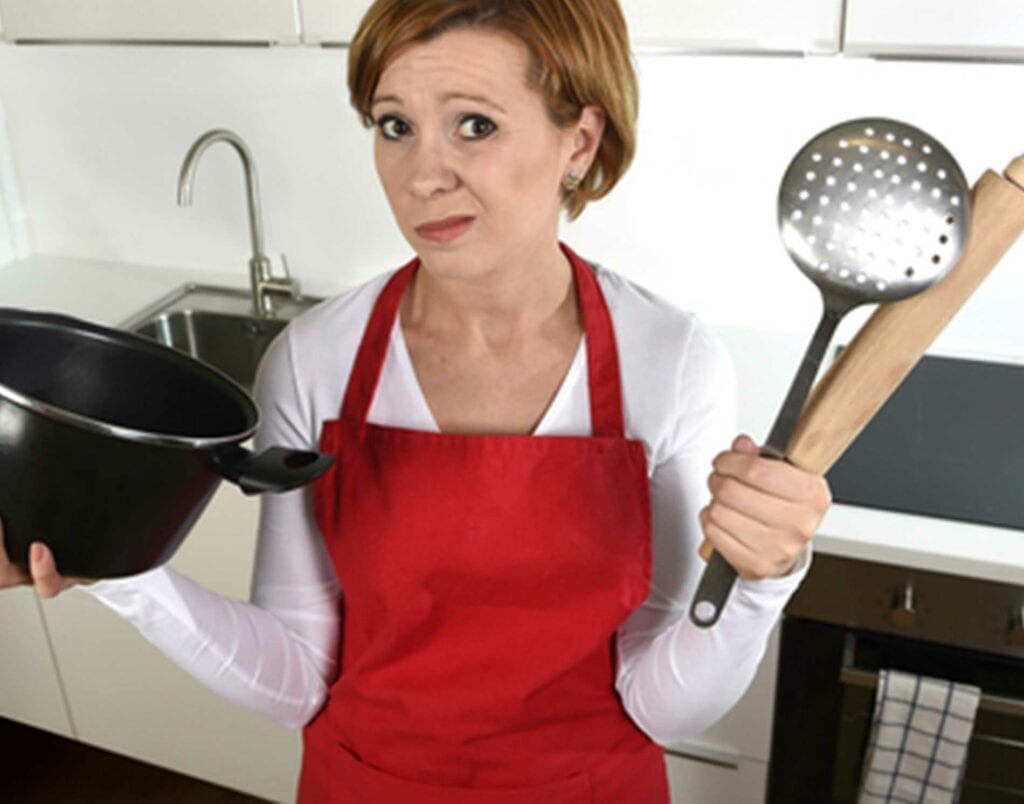 A woman holding two pots and a spatula in her hands.