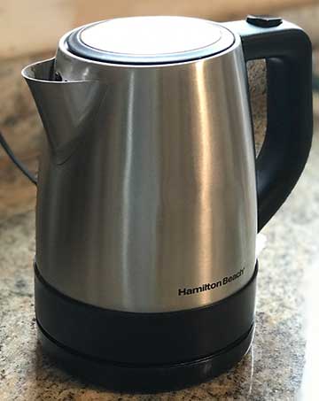 A silver and black electric kettle on top of a counter.