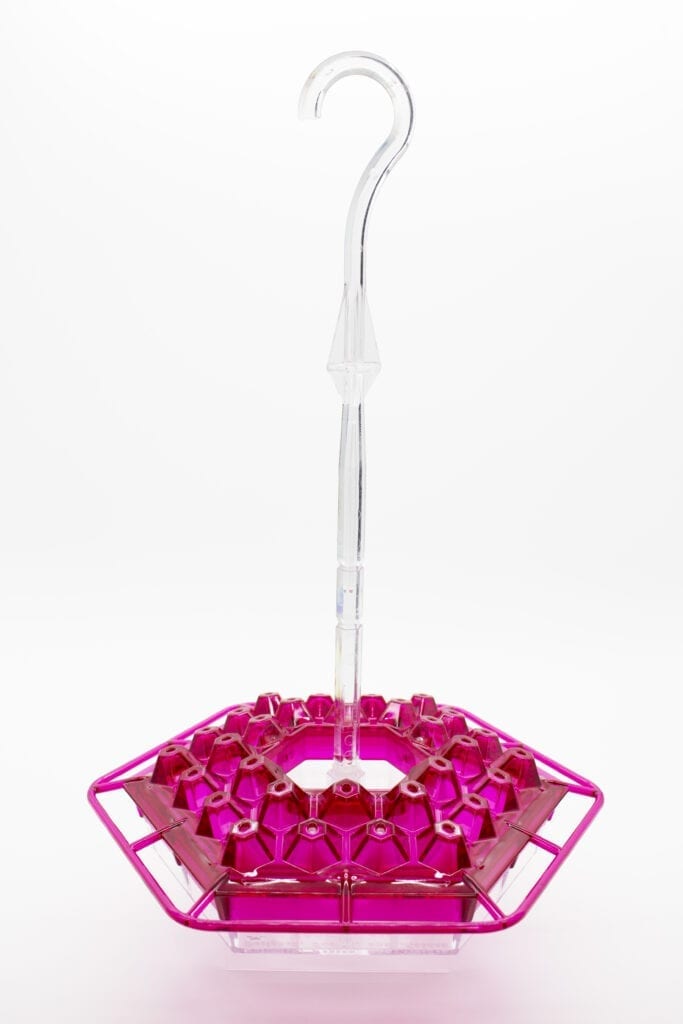A pink lip shaped bird feeder with a clear plastic tube.