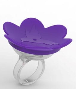 A purple flower shaped ring holder sitting on top of a white ring.