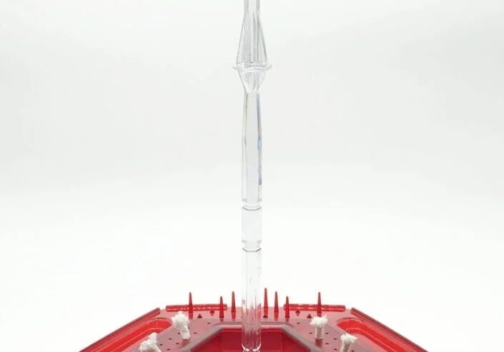 A red plastic container with a clear umbrella on top of it.